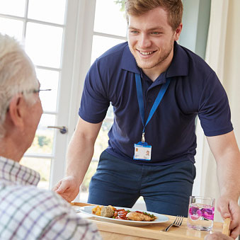 a caregiver bringing an elderly person food